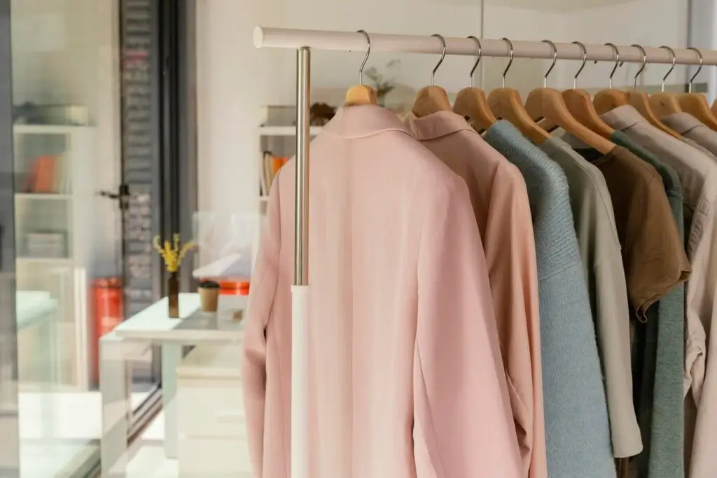 clothing rack displays a variety of shirts in soft colors