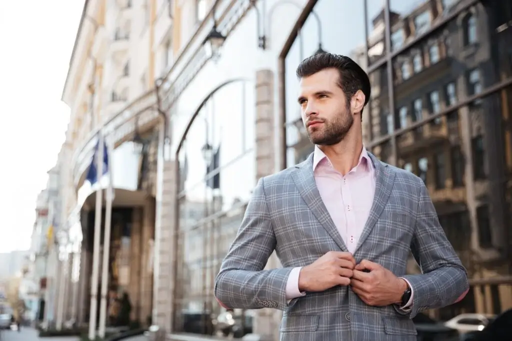 man in a tailored grey suit with a light pink shirt